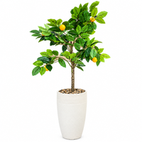 Artificial lemon tree with green leaves yellow fruit and cream pot